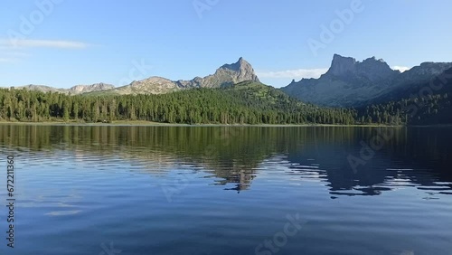 Small ripples on the surface of a large lake surrounded by high peaked mountains on a sunny summer evening. Lake Svetloe, Ergaki Nature Park, Krasnoyarsk Territory, Siberia, Russia. photo
