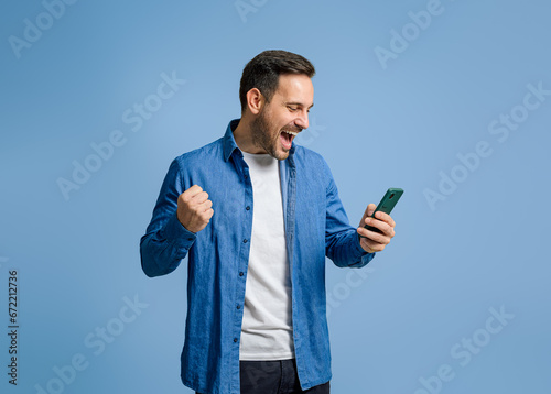 Bild auf Leinwand Businessman screaming and pumping fist after receiving good news over cellphone