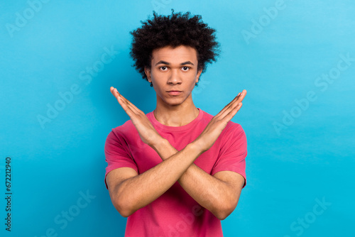 Photo of serious confident man with perming coiffure wear pink t-shirt holding arms crossed show stop isolated on blue color background