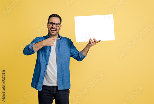 Quadro em tela Portrait of businessman laughing and pointing at blank white poster against yell