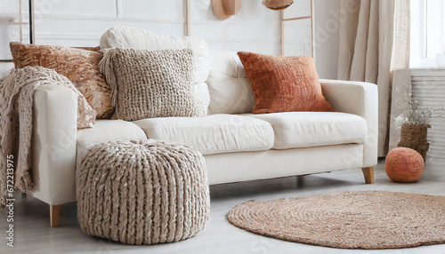 Knitted pouf near white fabric sofa with blanket and terra cotta pillows Scandinavian hygge style home interior design of modern