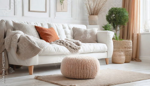 Knitted pouf near white fabric sofa with blanket and terra cotta pillows Scandinavian hygge style home interior design of modern photo