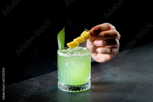 green cocktail with lime in a glass glass with ice and pieces of fruit, side view