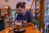 man drinking coffee in cafe with warm lighting 