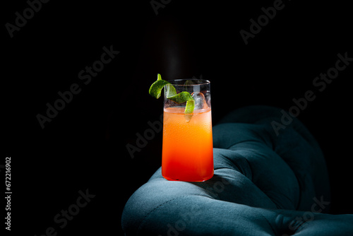 bright tropical cocktail with lime peel and gradient color in a transparent glass, side view