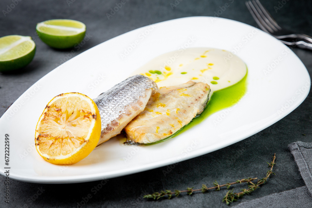 pieces of fried fish with sauce and fried lemon on a white plate side view pieces of fried fish with sauce and fried lemon on a white plate side view