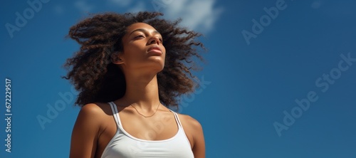 Young black woman looking at sunny blue sky