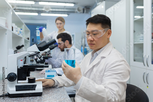 Serious thinking asian scientist working with microscope inside laboratory  man in white medical coat scientist working on sample research.