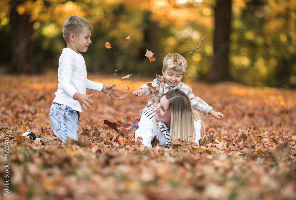 Happy young mother and two brothers walking in the autumn forest. Autumn outdoor activity for family with kids. Happy mothers day. Happy young mother and two brothers walking in the autumn forest. Autumn outdoor activity for family with kids. Happy mothers day.