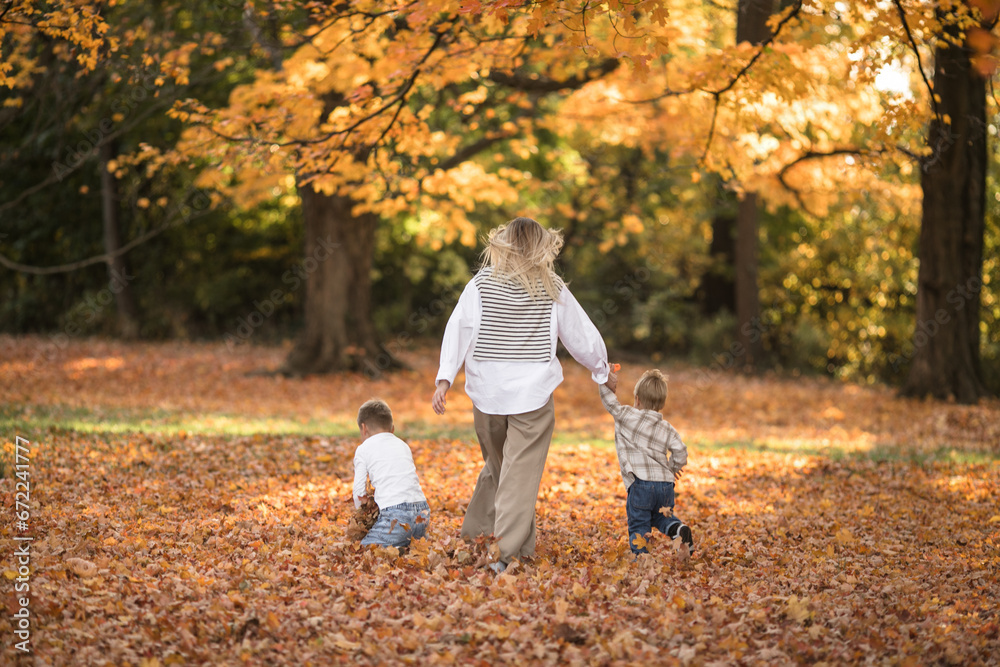 Happy young mother and two brothers walking in the autumn forest. Autumn outdoor activity for family with kids. Happy mothers day. Happy young mother and two brothers walking in the autumn forest. Autumn outdoor activity for family with kids. Happy mothers day.