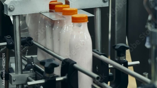 Dairy food products in multiple plastic bottles are advancing on a conveyor belt. Bottled milk products going through a conveyor at dairy food facility. Processing of dairy food on industrial conveyor photo