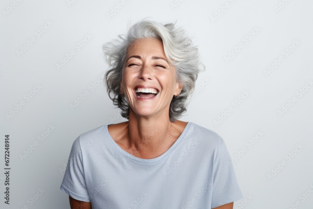 Elegant mid adult woman against white background. Stylish mature woman in white casuals looking away and smiling.