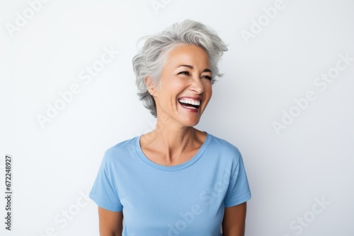 Elderly beautiful woman with a short pixie haircut in a blue sweater on a gray background photo