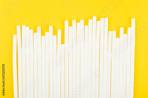 White drinking straws on yellow background.