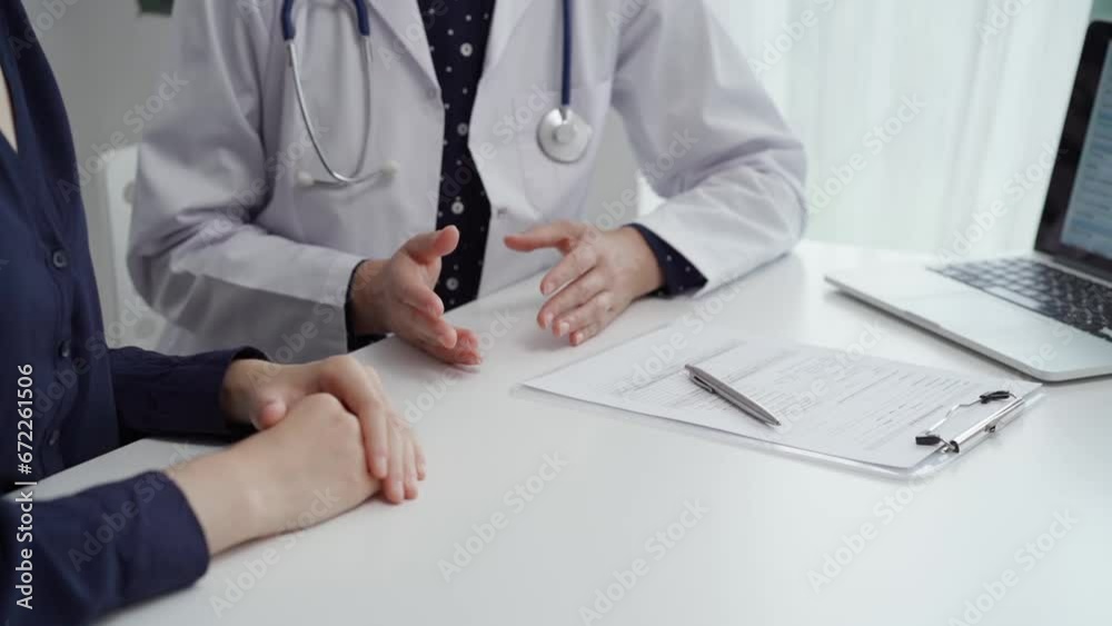 Doctor and patient sitting at the table and discussing something. The pediatrician in a blue dotted blouse and white medical coat is gesturing actively. Medicine concept Doctor and patient sitting at the table and discussing something. The pediatrician in a blue dotted blouse and white medical coat is gesturing actively. Medicine concept