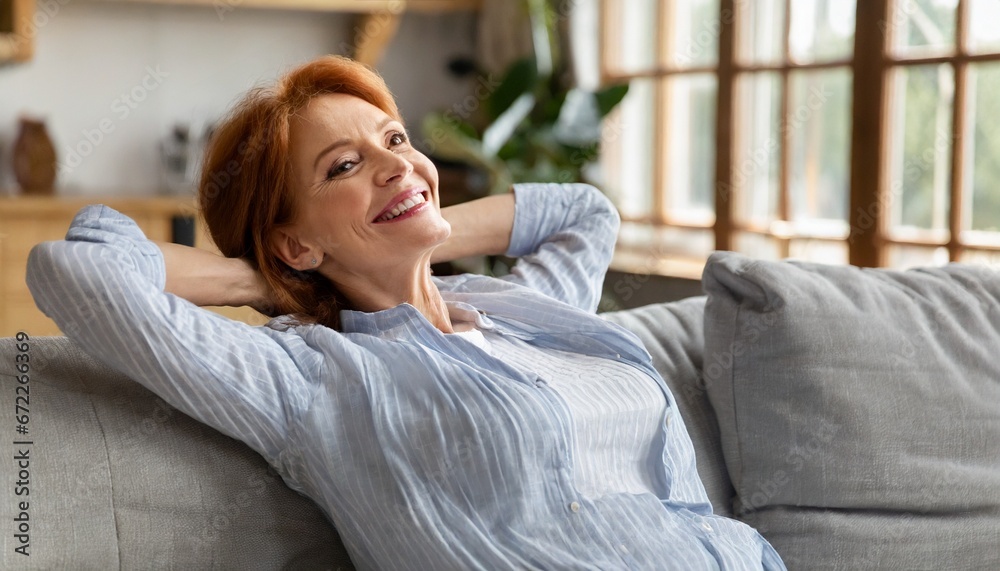 Smiling relaxed mature old woman resting dreaming sitting on couch at home