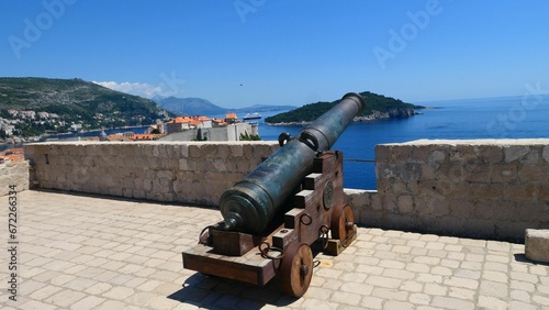 Old cannon on the fortress Lovrijenac with the old town of Dubrovnik and the island of Lokrum photo