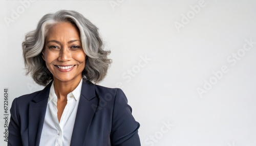 Smiling beautiful mature business woman standing isolated on white background. Older senior businesswoman, 60s grey haired lady professional coach looking at camera, close up face headshot portrait photo