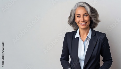 Smiling beautiful mature business woman standing isolated on white background. Older senior businesswoman, 60s grey haired lady professional coach looking at camera, close up face headshot portrait photo