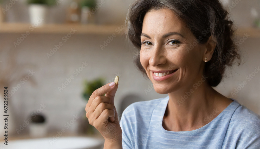 Closeup portrait of happy middle aged 50s woman holding pill taking dietary supplements. Portrait of smiling adult attractive woman taking collagen vitamins health in menopause Closeup portrait of happy middle aged 50s woman holding pill taking dietary supplements. Portrait of smiling adult attractive woman taking collagen vitamins health in menopause