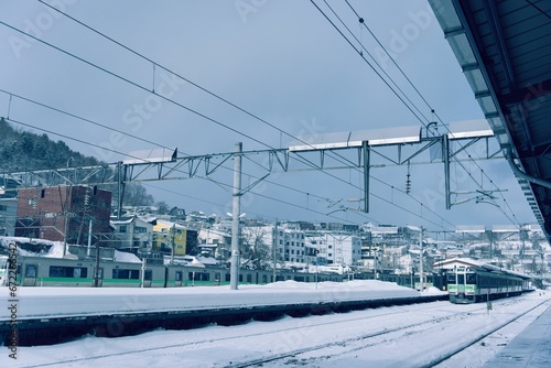 Busy train station, featuring various buildings and railway lines on the snowy winter day