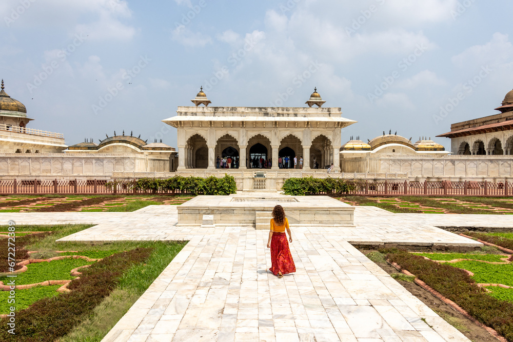 Woman walks through the great Agra Fort in Agra, India, with its wonderful architecture on a cloudy day - obrazy, fototapety, plakaty 