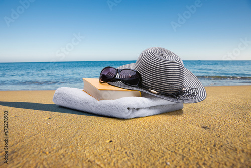 Buch, Handtuch, sonnenbrille  und Sonnenhut am Strand photo