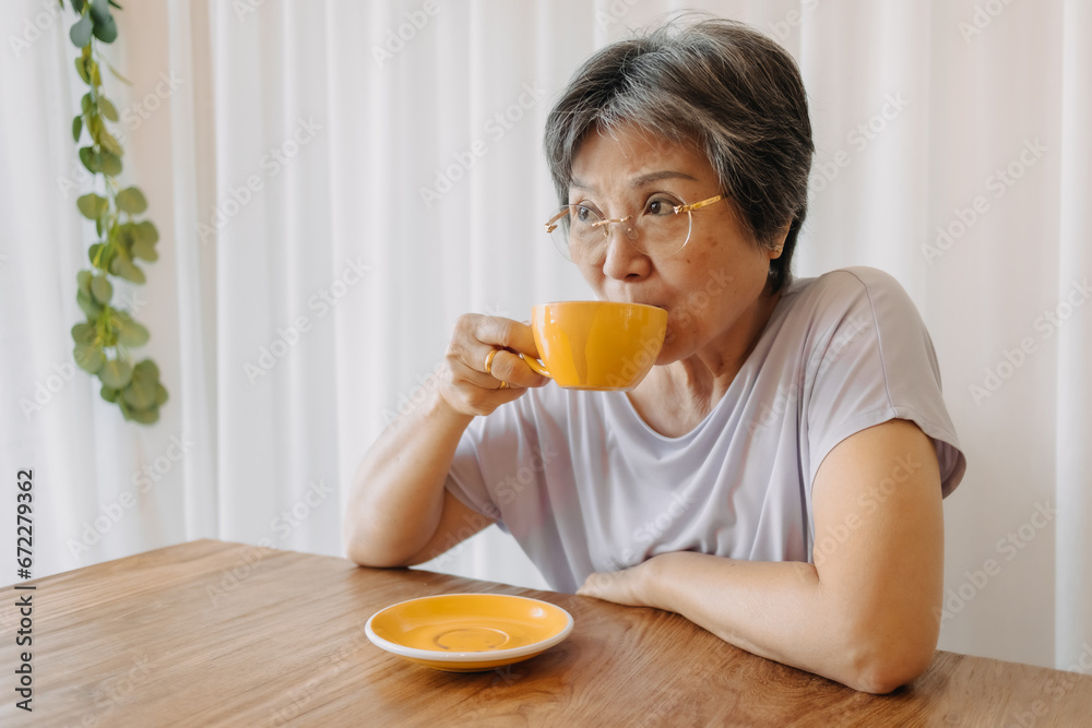 Asian old woman wear eye glasses holding cup and drinking coffee tea alone at home cafe, Happy smiling, relaxing time, health care senior insurance concept. Asian old woman wear eye glasses holding cup and drinking coffee tea alone at home cafe, Happy smiling, relaxing time, health care senior insurance concept.