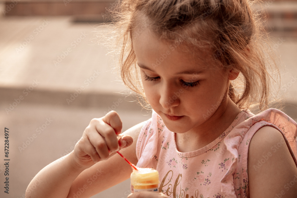 A little girl with red or brown hair blows soap bubbles. The concept of a carefree, happy, peaceful childhood. Close-up, happiness A little girl with red or brown hair blows soap bubbles. The concept of a carefree, happy, peaceful childhood. Close-up, happiness