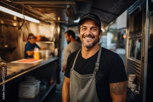 Smiling mid adult male owner looking away while standing in food truck photo