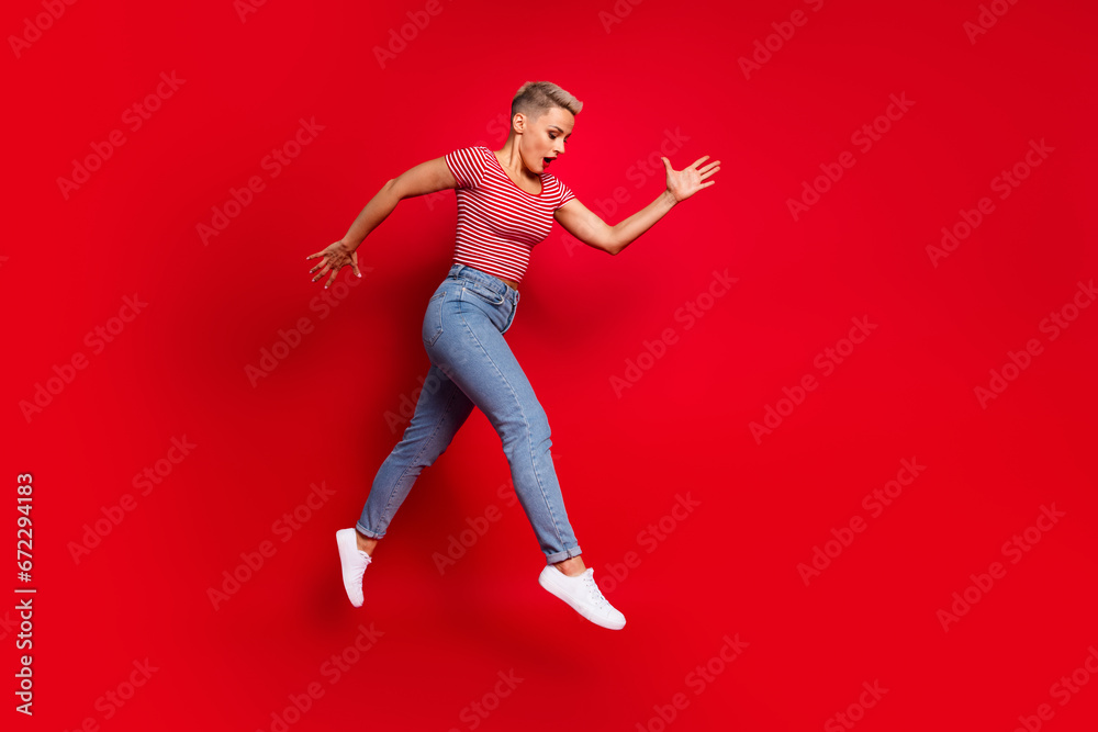 Full length profile side photo of funky crazy girl wear trendy clothes moving empty space isolated on red color background