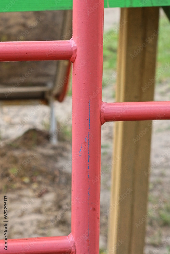 part of a metal structure made of red iron pipes on the street