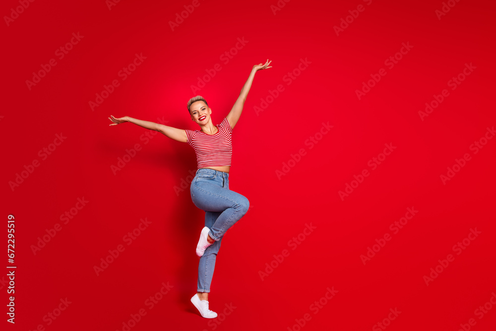 Full length photo of lovely adorable girl wear stylish clothes presenting empty space novelty offer isolated on red color background