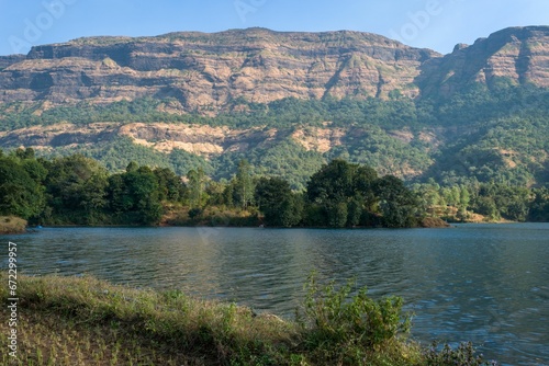 Fototapeta Naklejka Na Ścianę i Meble -  Scenic view of Arthur Lake in Bhandardara, India is seen, with lush green hills and trees