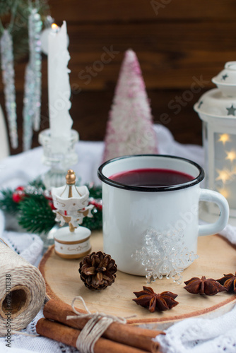 New Year's hot drink with spices on a white knitted blanket. Festive home decoration, Christmas trees and burning candles