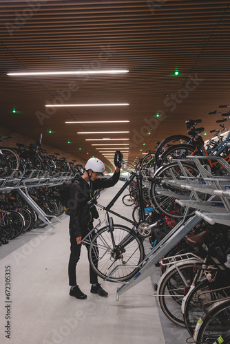 Traveller is surprised by the huge underground cycle station under the main overpass in Amsterdam, Netherlands. Inserting the wheel into the attachment and bike handle
