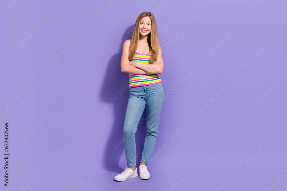 Full length photo of lovely teen blonde lady folded hands confident dressed stylish striped garment isolated on violet color background Full length photo of lovely teen blonde lady folded hands confident dressed stylish striped garment isolated on violet color background