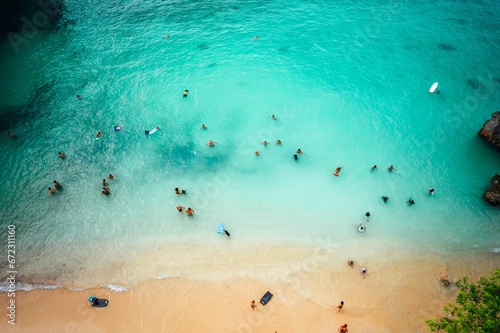 Aerial view of a paradise-like bustling beach with white sand and turquoise-colored waves lapping up © Wirestock