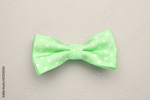 Stylish spring green bow tie with polka dot pattern on light grey background, top view
