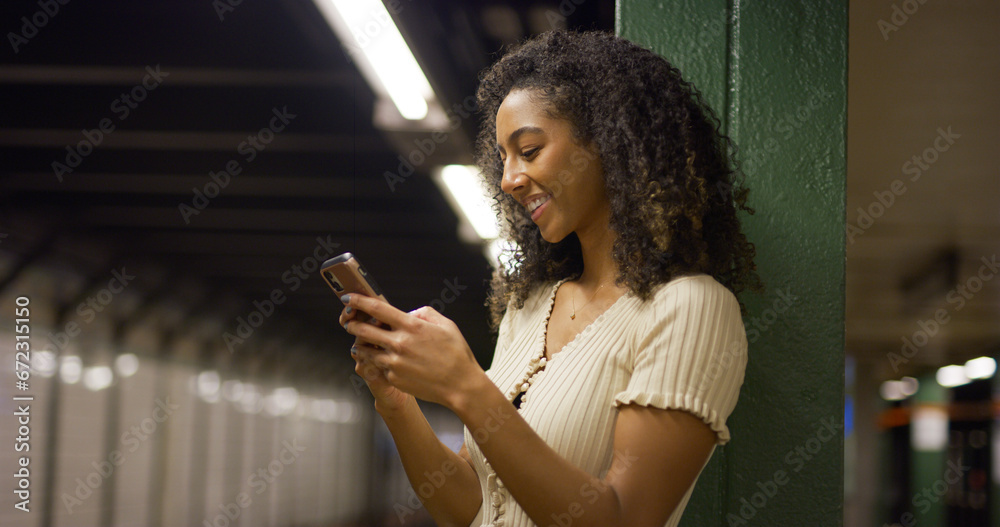 Young black woman using smartphone at a subway platform Young black woman using smartphone at a subway platform