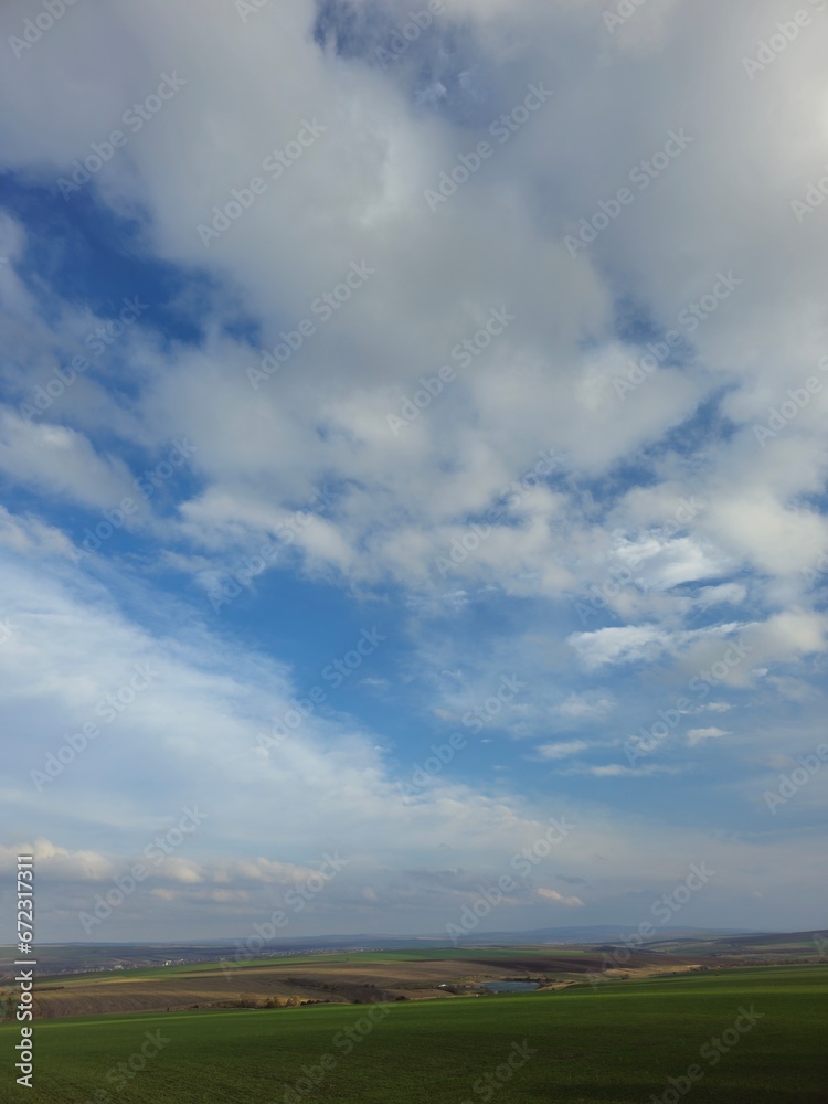 A large grassy field with clouds in the sky A large grassy field with clouds in the sky