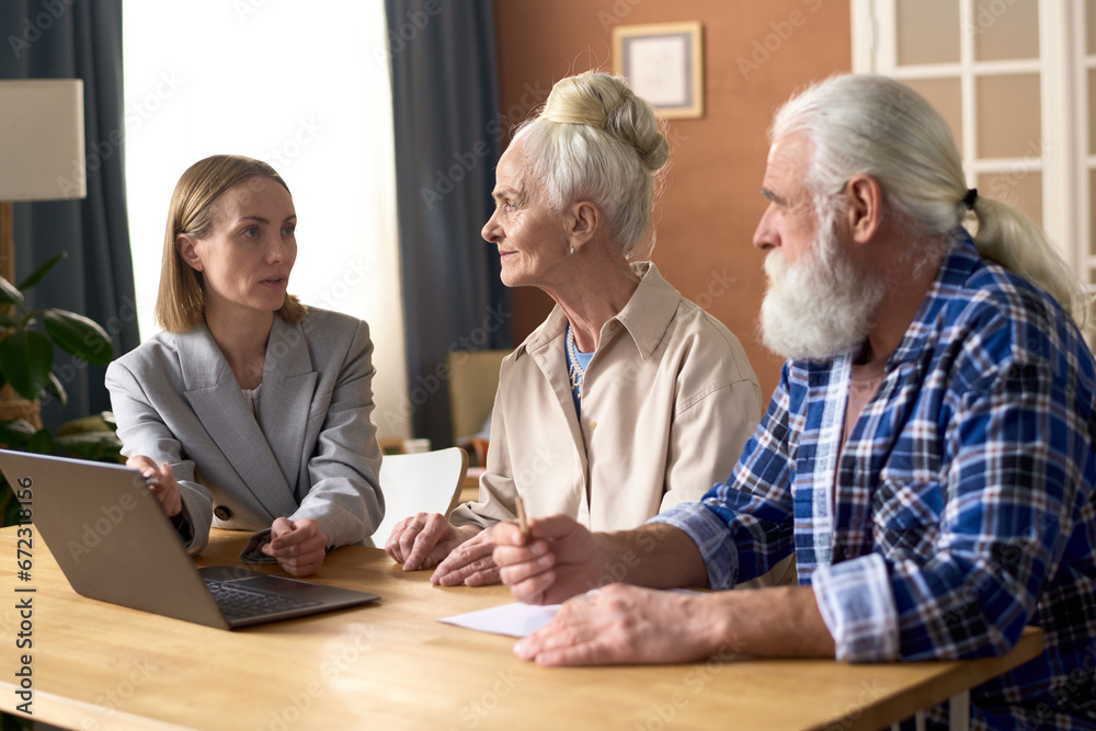 Financial advisor using laptop and talking to senior couple during meeting at home Financial advisor using laptop and talking to senior couple during meeting at home