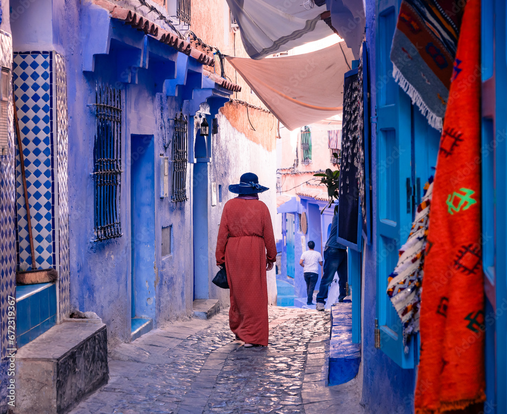 woman walking on the blue streets of Chefchaouen Morocco