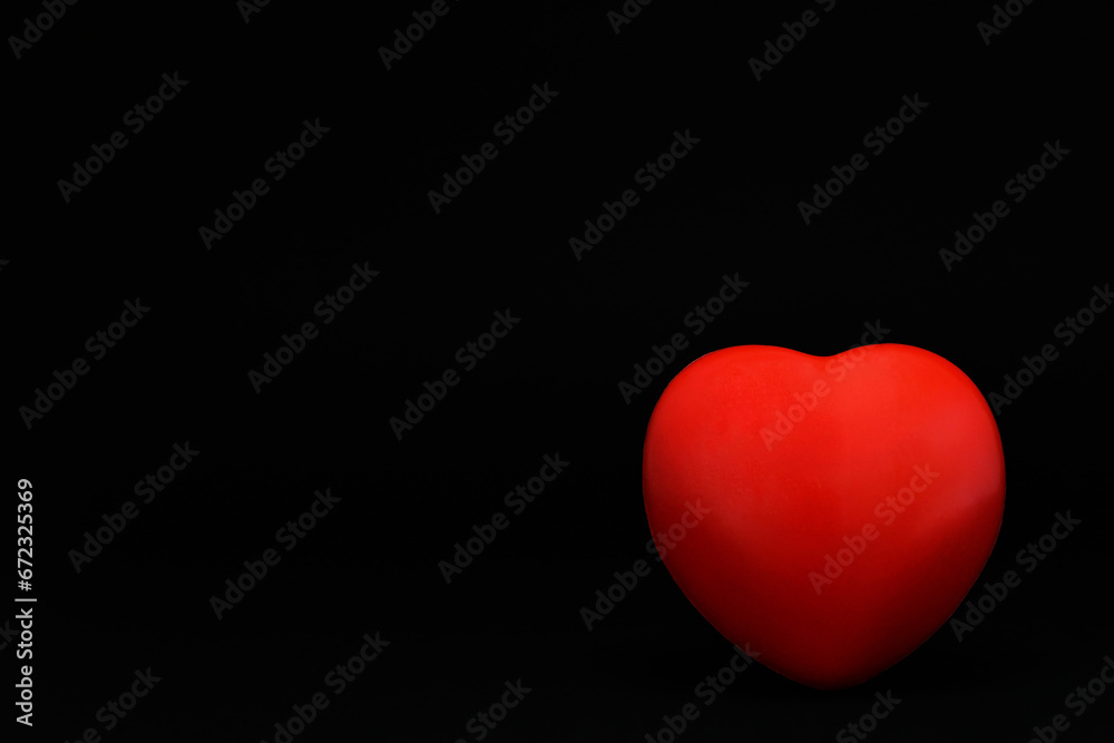 Corazón rojo sobre fondo negro, espacio para texto al lado izquierdo, concepto día de san Valentín. Corazón rojo sobre fondo negro, espacio para texto al lado izquierdo, concepto día de san Valentín.