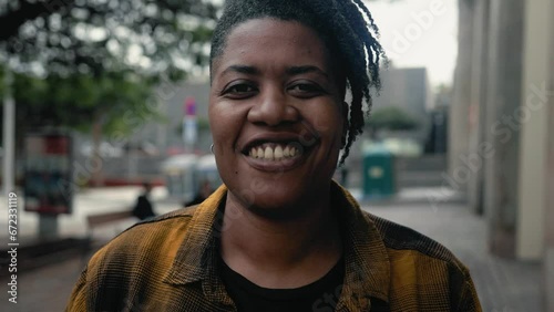 Happy African woman smiling in front of a camera in the city