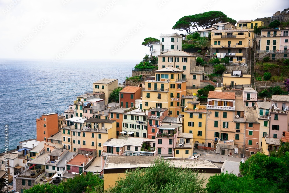 Aerial view of Riomaggiore with a town built into the side of a steep cliff, overlooking the sea