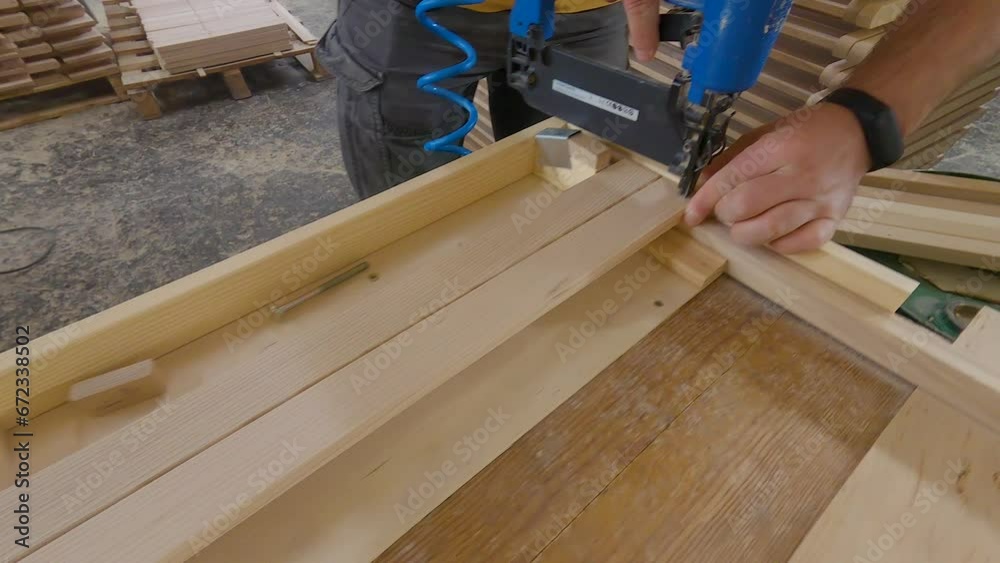 Craftsman in a carpentry workshop hammers nails with a pneumatic hammer. Making a stool Craftsman in a carpentry workshop hammers nails with a pneumatic hammer. Making a stool