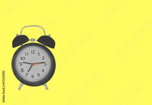 a black alarm clock, on a yellow background