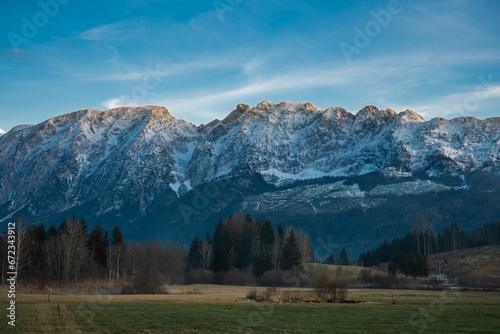 Scenic view of a mountain range covered with snow at golden hour against a green field