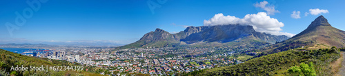 Panoramic scene of Cape Town, South Africa. Table Mountain, Lions Head and Signal Hill against a blue sky background, overlooking the city. Aerial view of the urban and natural environments